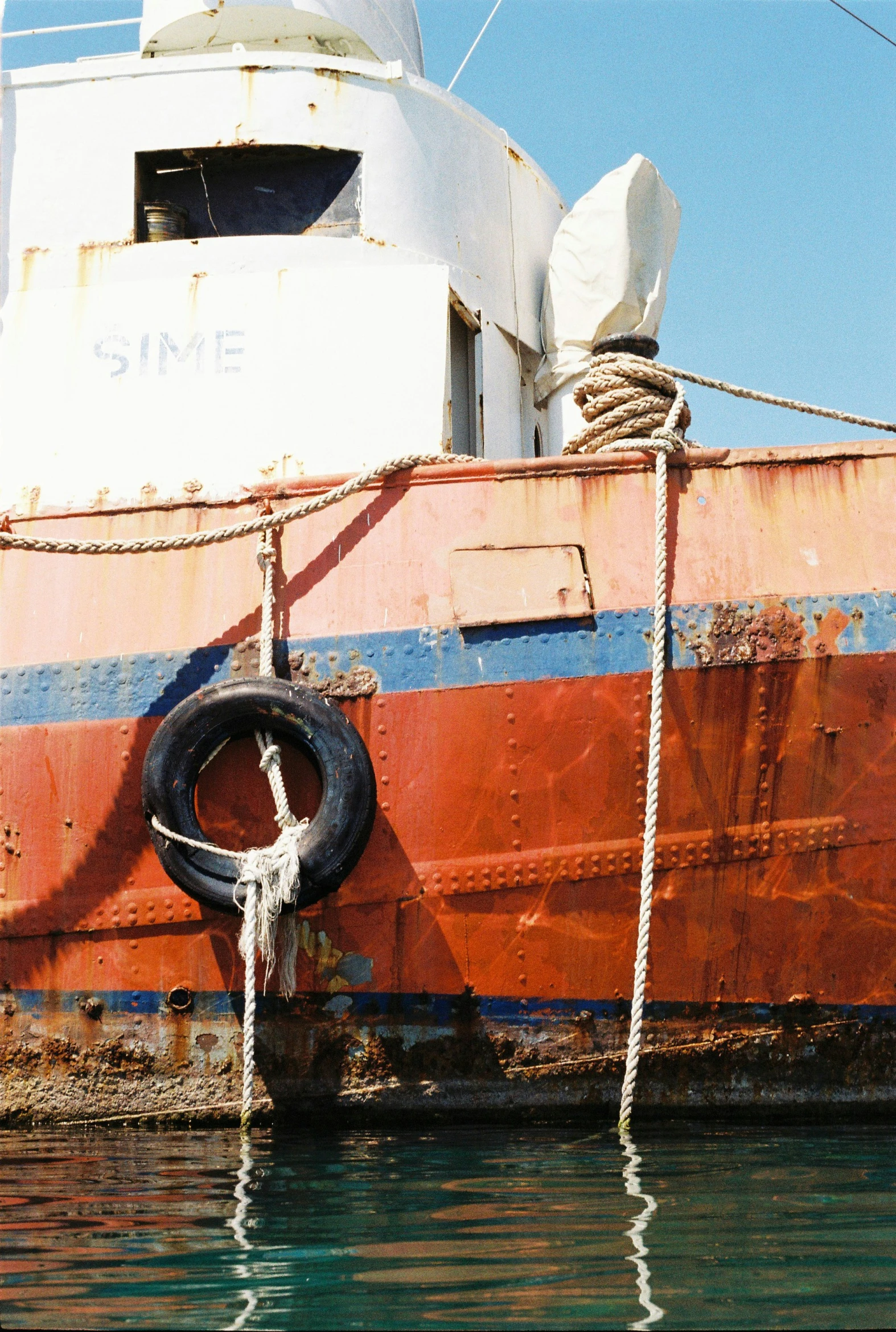 old red, blue and white ship anchored at dock