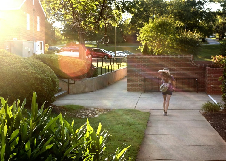 a woman walking in the sun holding onto her hat