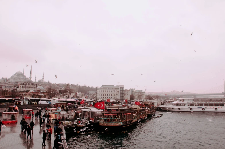 people walking along the side of a river by boats