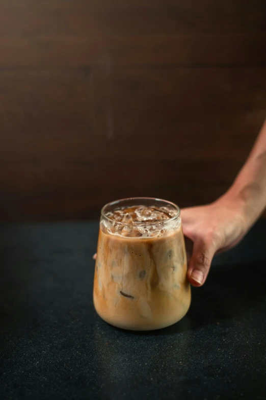 someone holding their hand near a drink on the table