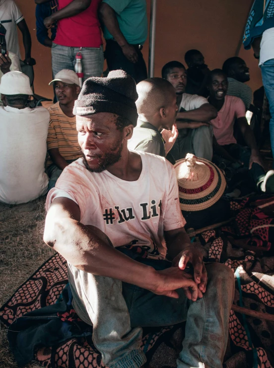 a man sitting on the ground with his hand in his pocket