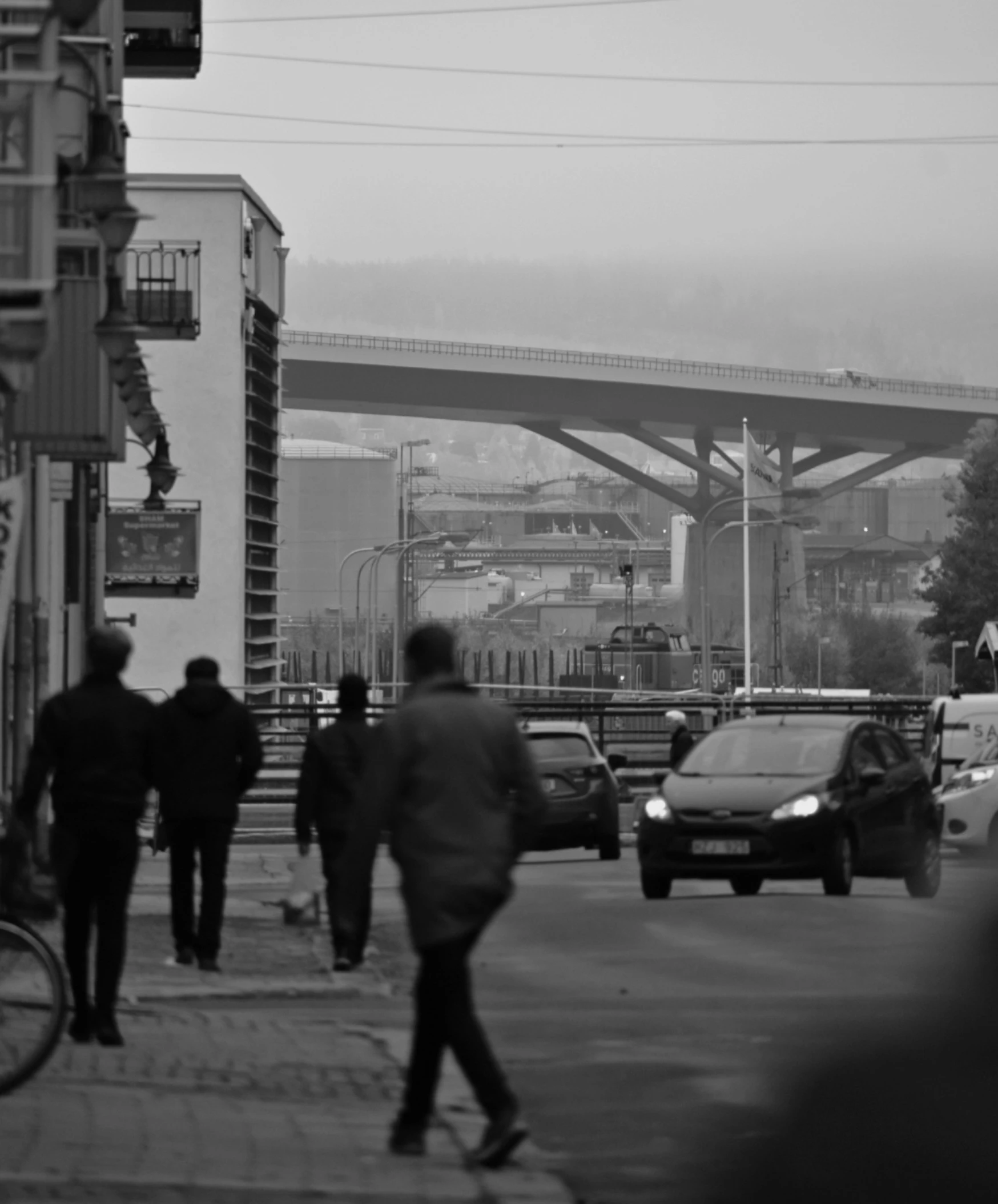 a street with cars, buses, and a bridge