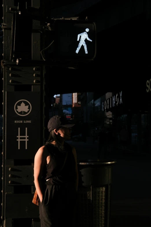 a woman standing on a city street, in front of a street light