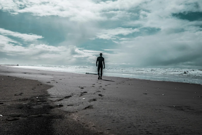 a man standing on top of a sandy beach near the ocean