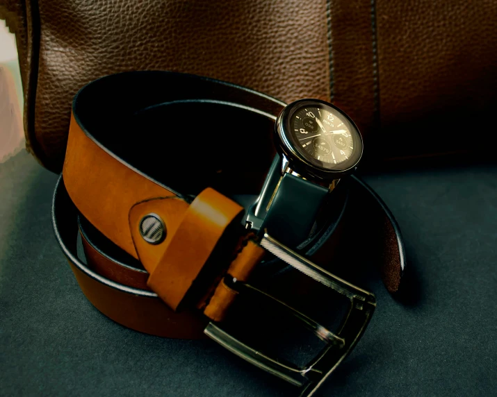 the leather belt is resting next to the purse