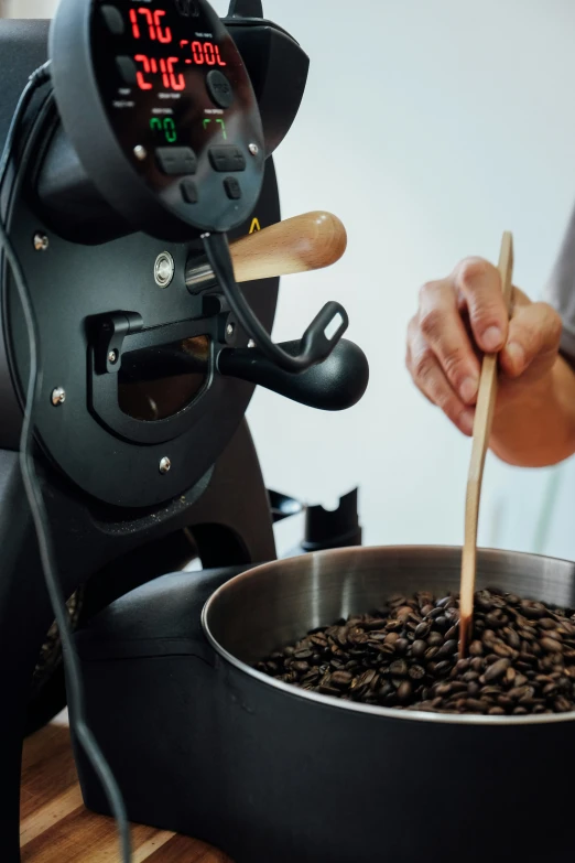 a person stirring some coffee beans in a pot