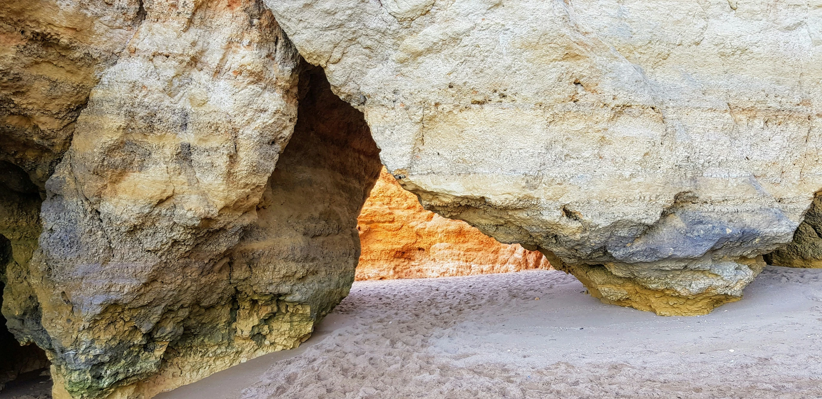 a lone bird sits under two large rocks