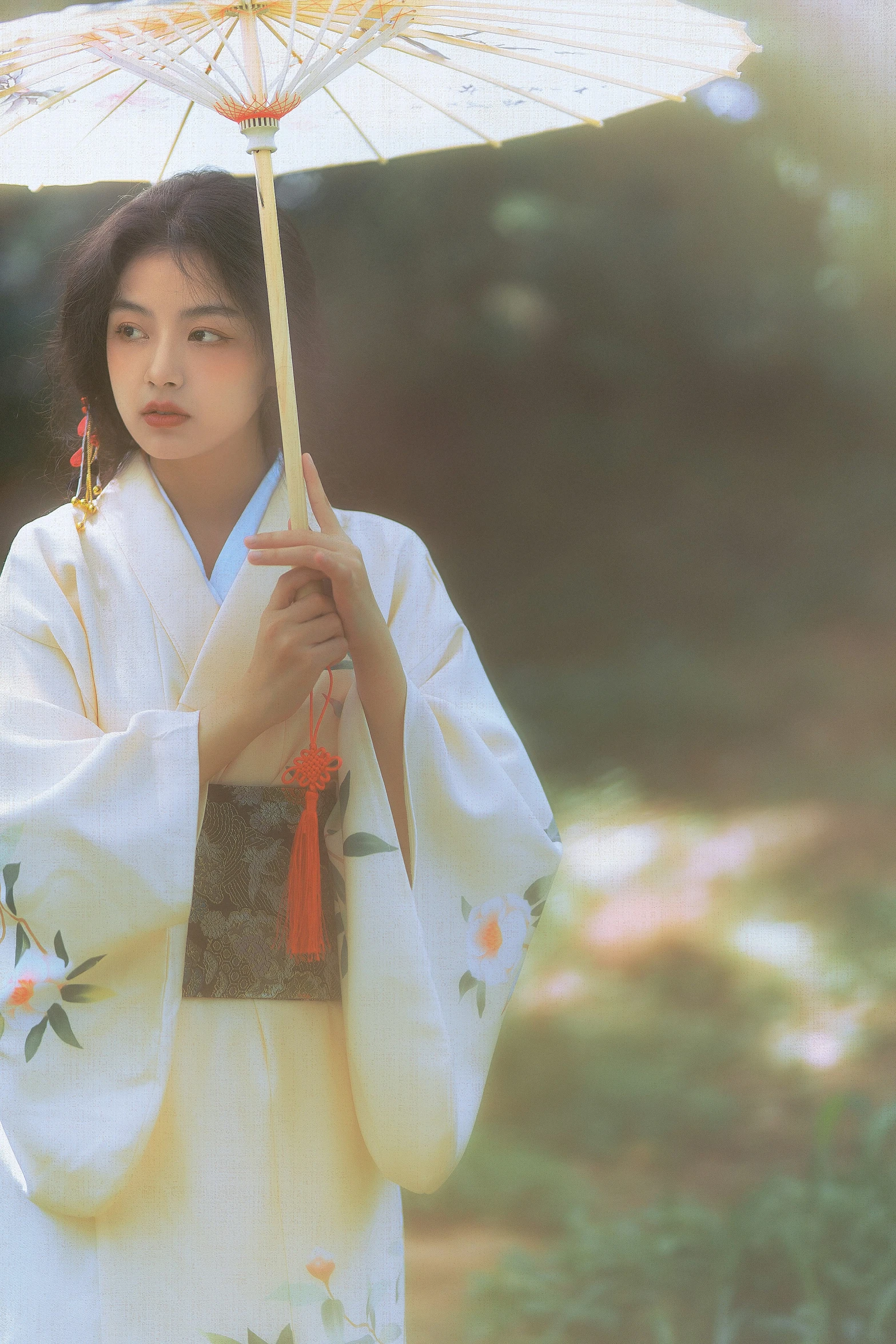 an oriental woman in traditional garb and holding an umbrella