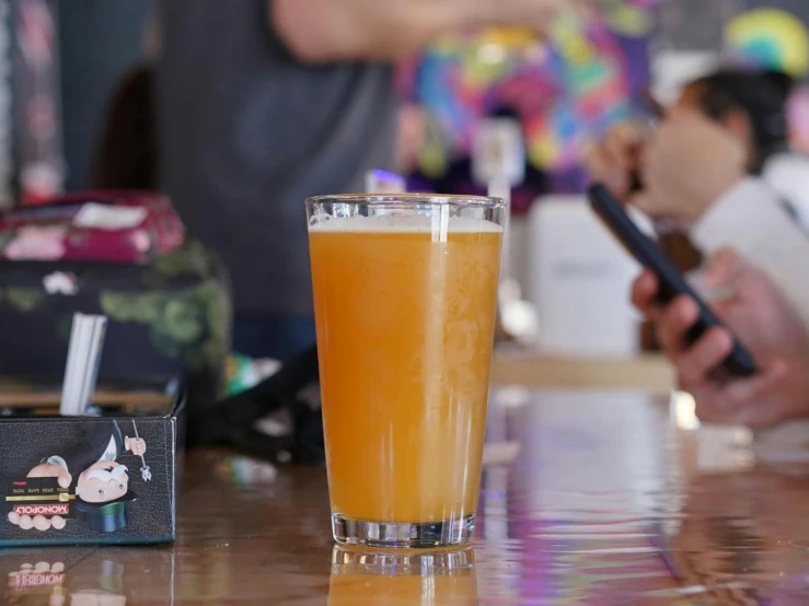 a glass on the table has a drink and phone