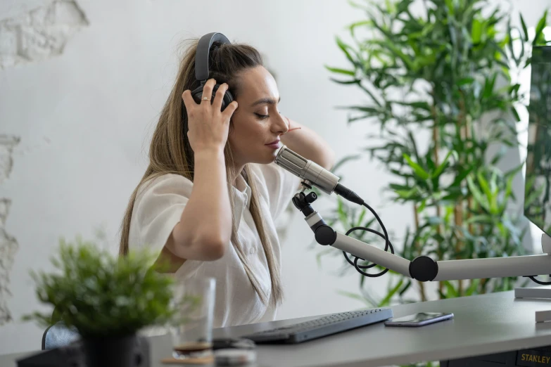 a woman is sitting at a desk in front of a microphone