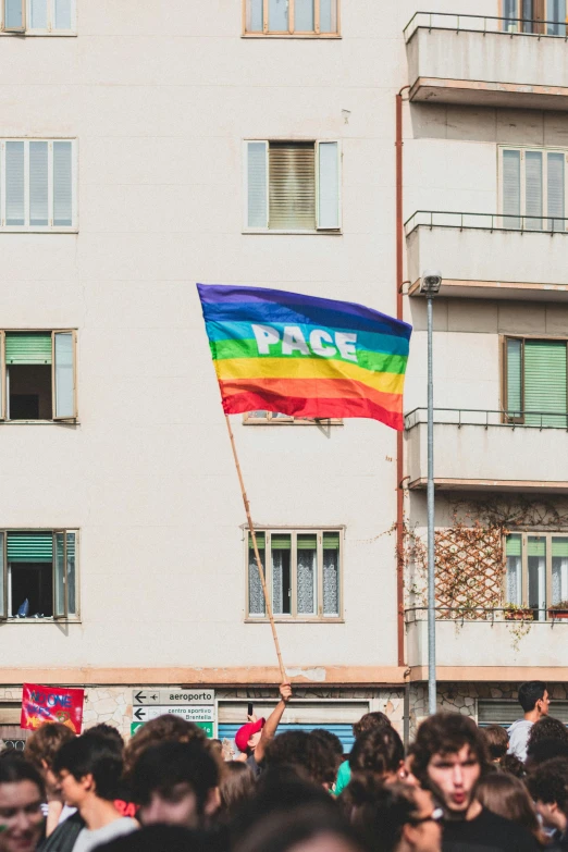 a man holding a rainbow flag near an apartment building