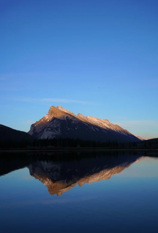 a mountain near some water and a clear sky