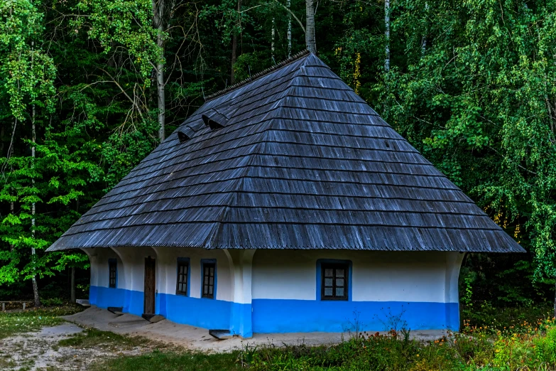 a white and blue house with a small gray roof in the forest