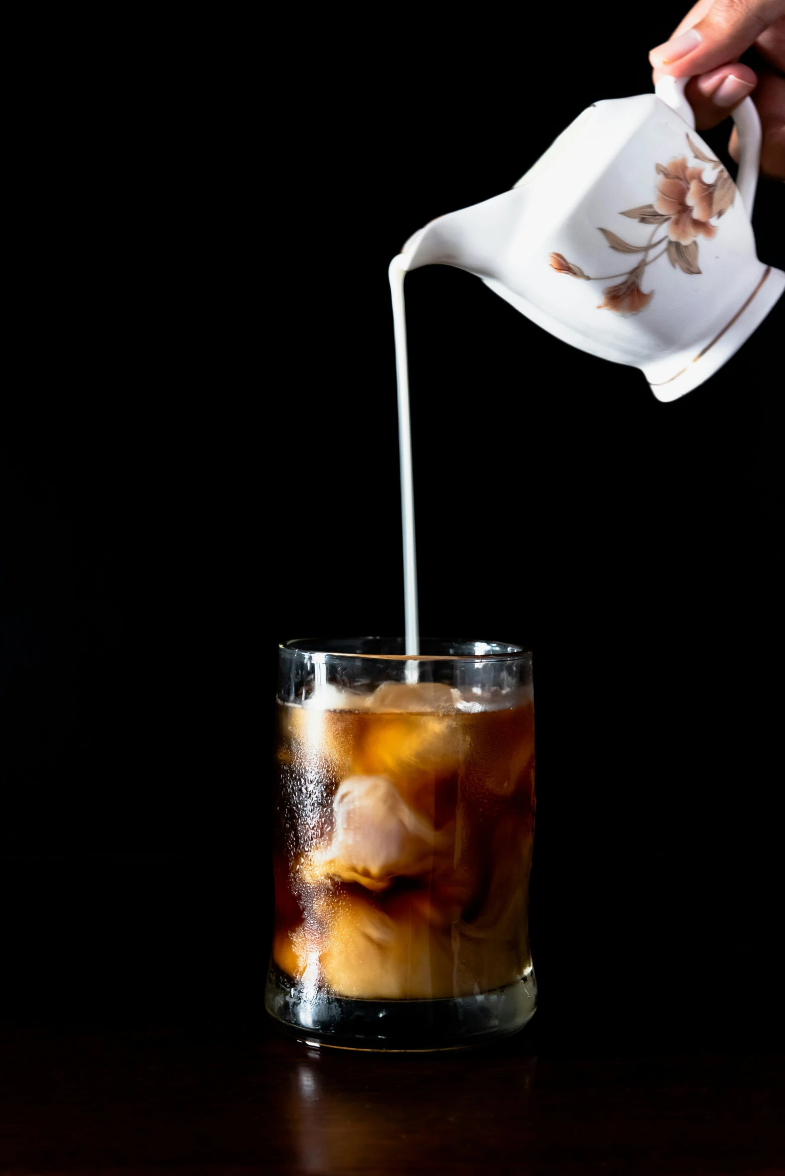 a person pours milk from a pot into a drink