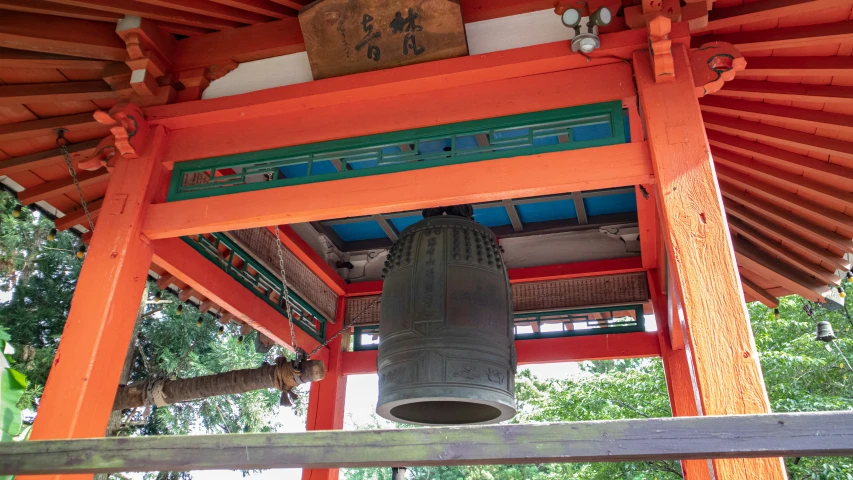 bells in the middle of a tower and trees behind it