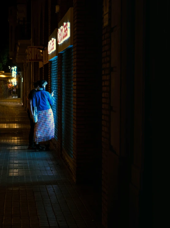 people are walking by a store at night