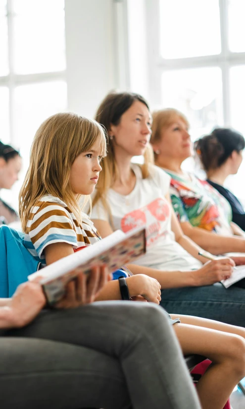 children sitting in a row and listening to speakers