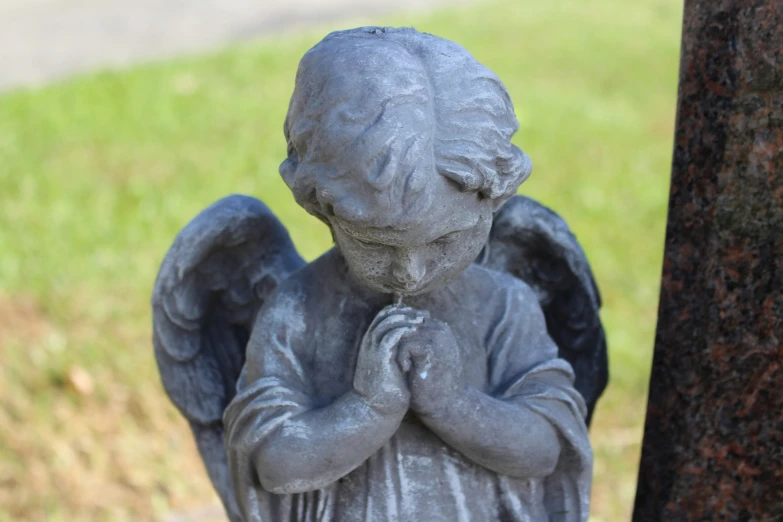 a statue of an angel is outside next to a tree