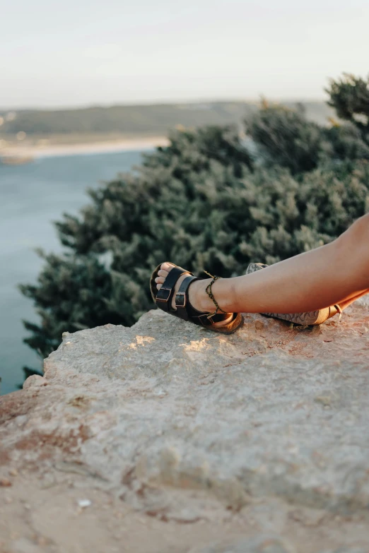 a person with sandals is laying on a rock