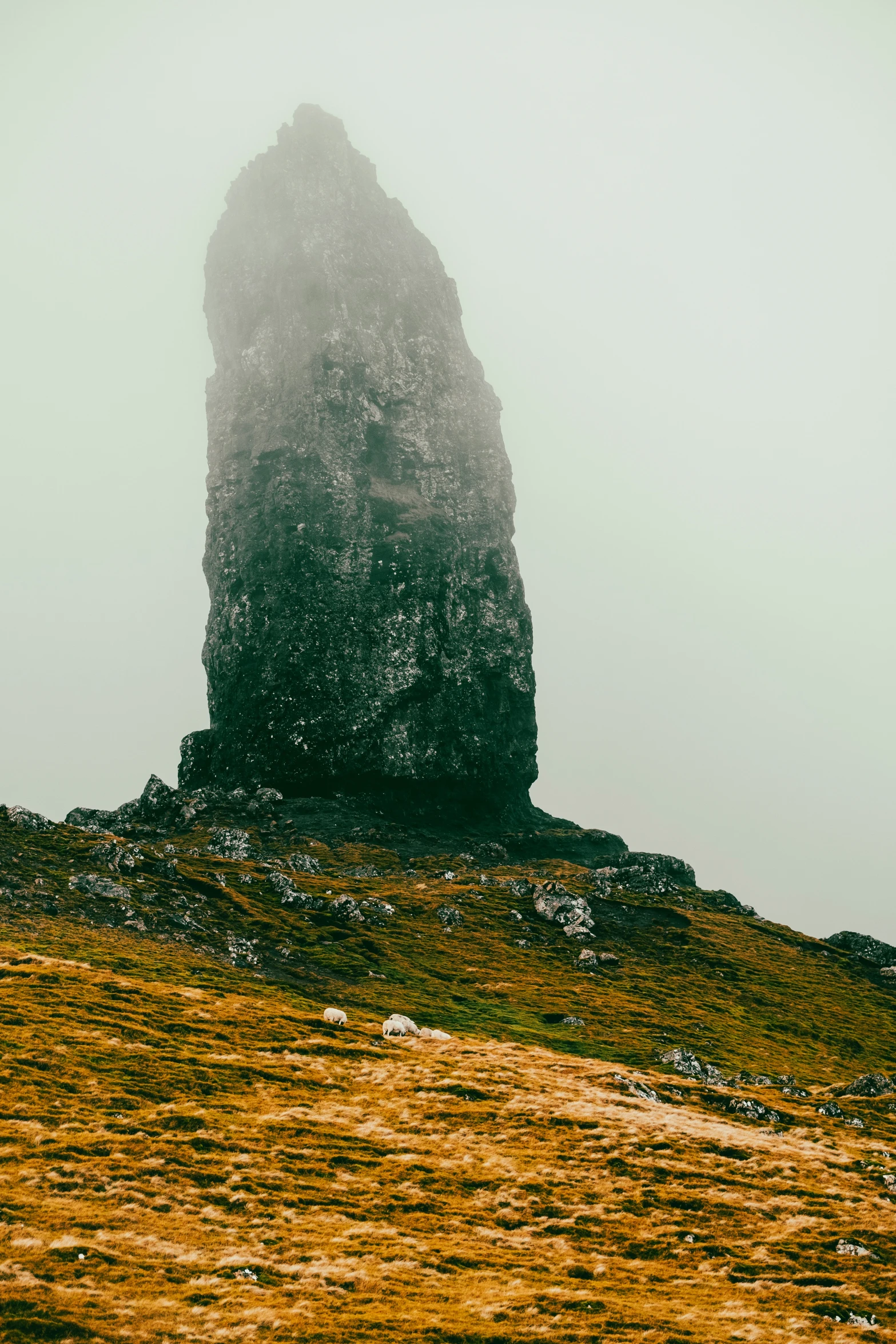 a very tall rock type object on a hill with fog