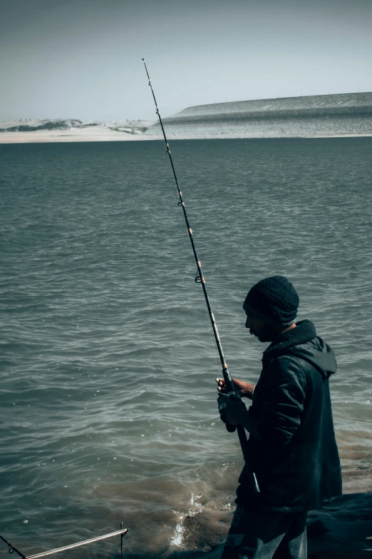 man fishing in a body of water on a cloudy day