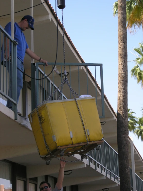 a man lifts a large piece of luggage out of a balcony