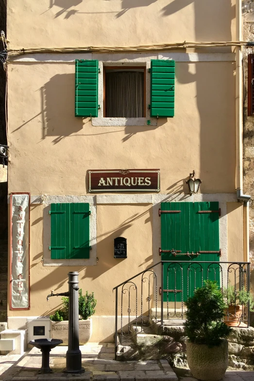 the front of an apartment building with green shutters