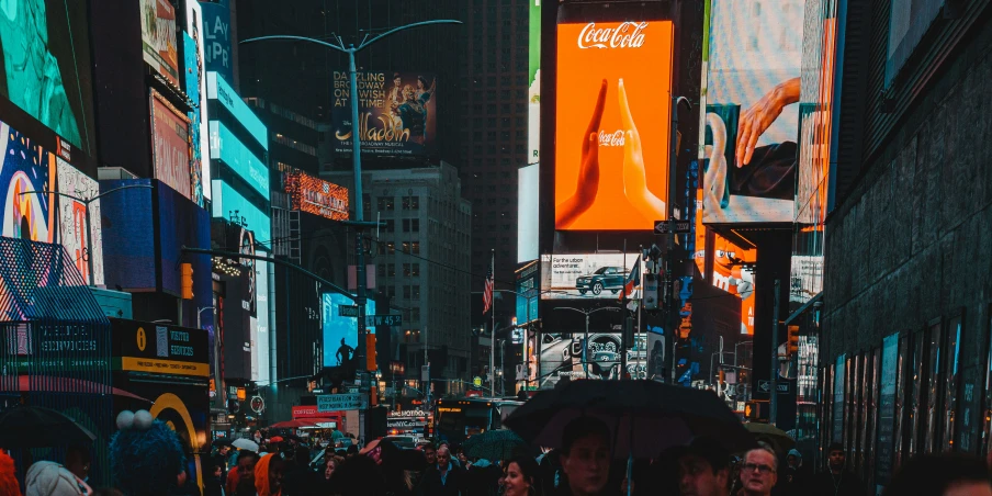 people walking down the street under a large screen display