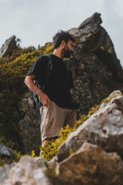 man with a backpack walks near some rocks