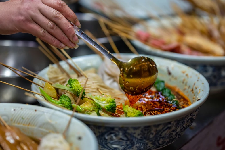 tongs being used over a bowl of food