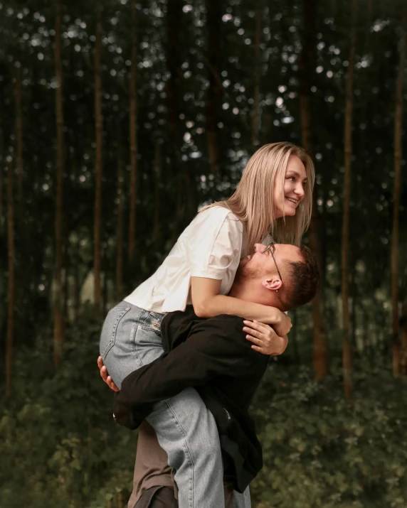 a woman and man hugging with trees in the background