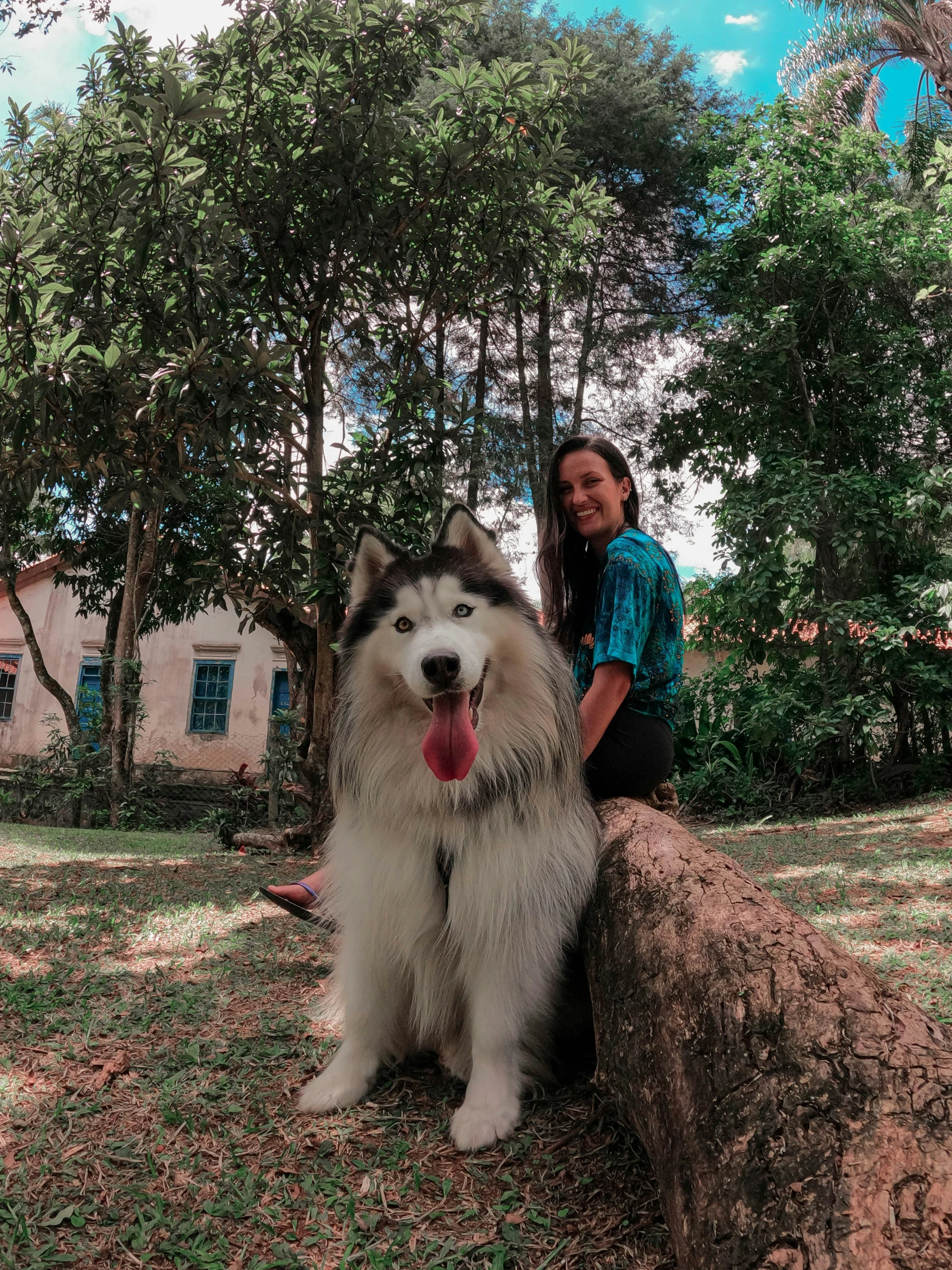 woman kneeling on log posing for camera with dog