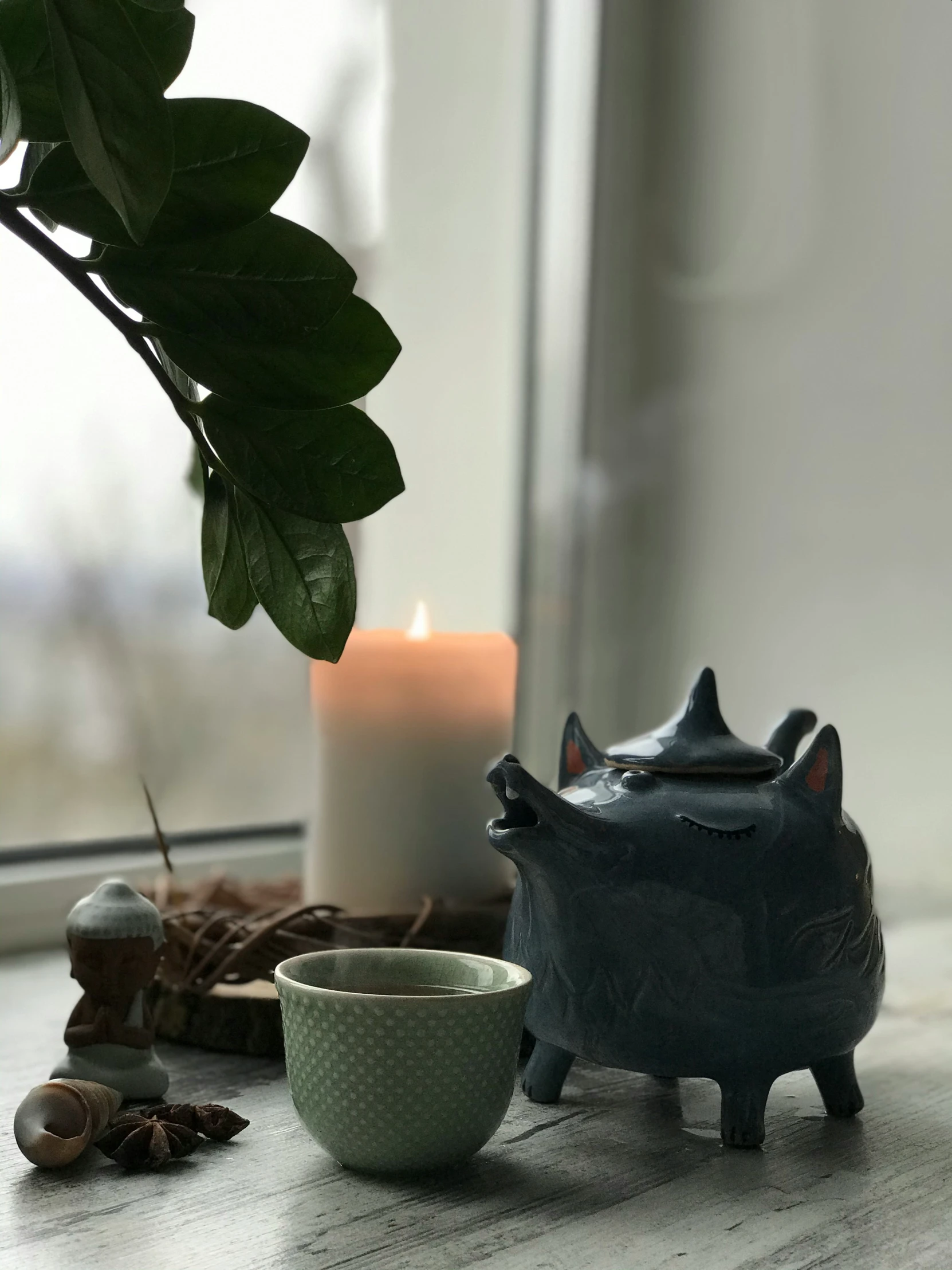 a candle sits next to a tea cup on a table