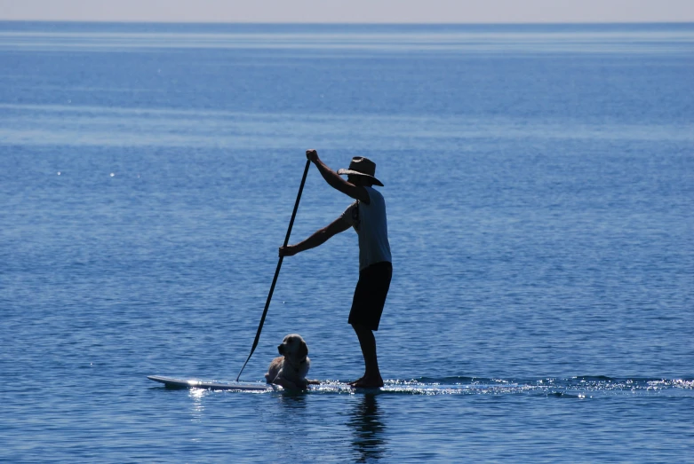 man on surfboard paddle boarding in ocean next to young child