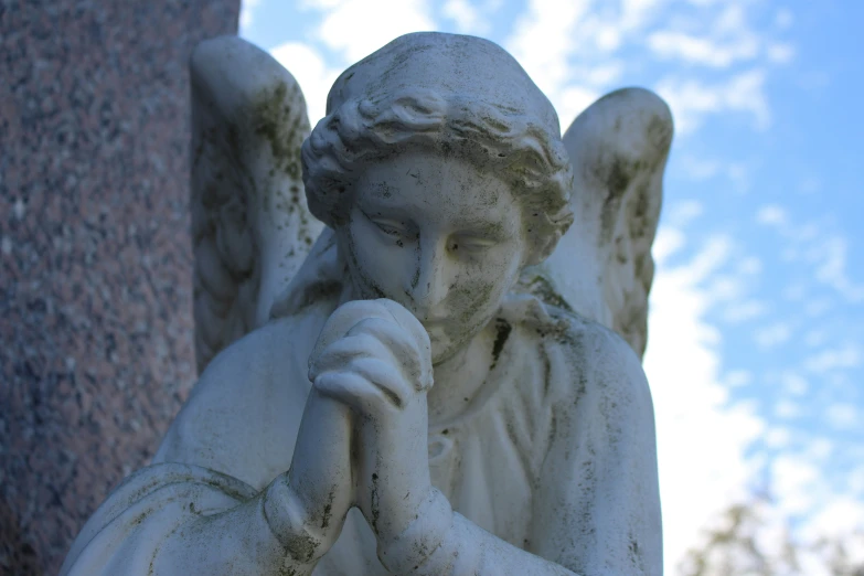 a statue of an angel with hands clasped
