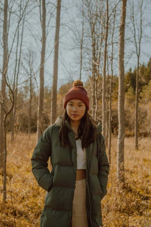 a girl with a beanie standing in the forest