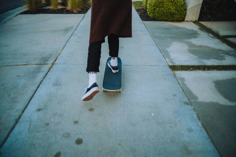 the person is standing on the edge of a sidewalk holding onto a skateboard