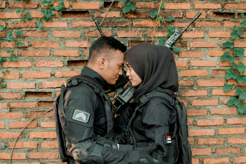 a man and woman standing in front of a brick wall next to each other