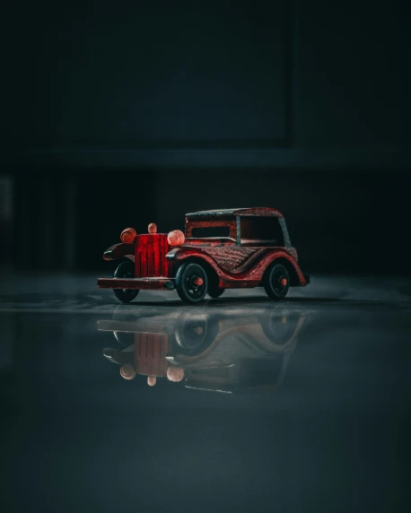a red old fashion truck parked on a reflective surface