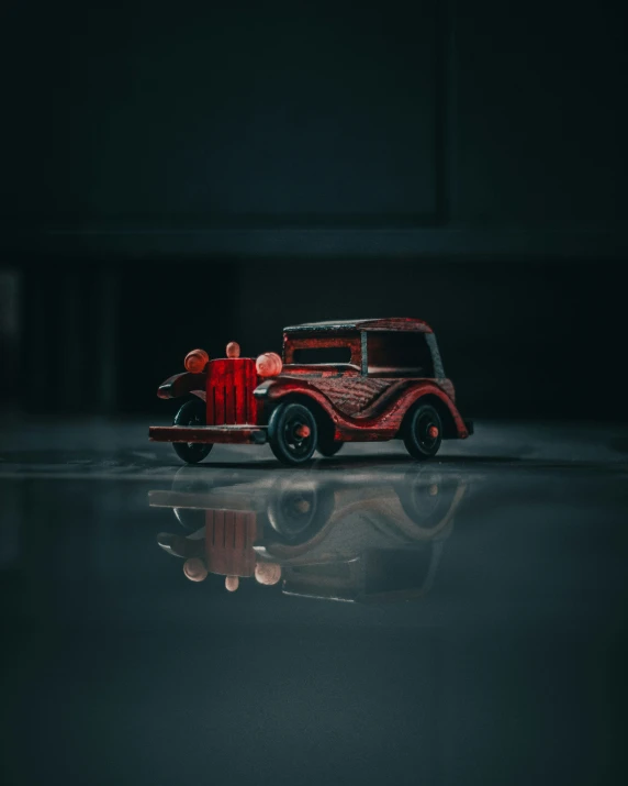 a red old fashion truck parked on a reflective surface