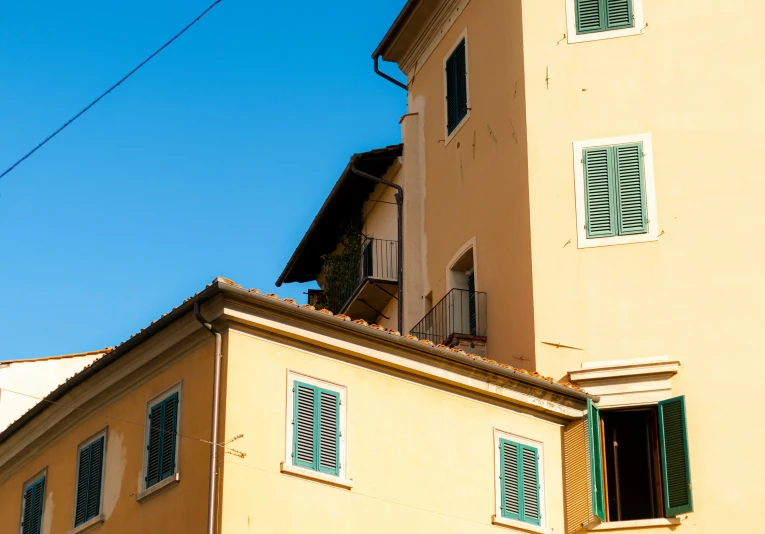 an apartment building with a balcony and green shutters