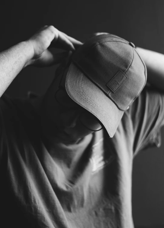 a person holds their cap and pulls his hair back