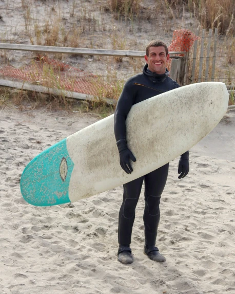 a surfer is holding his surf board on the beach