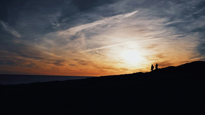 a man and woman standing on a hill by the ocean