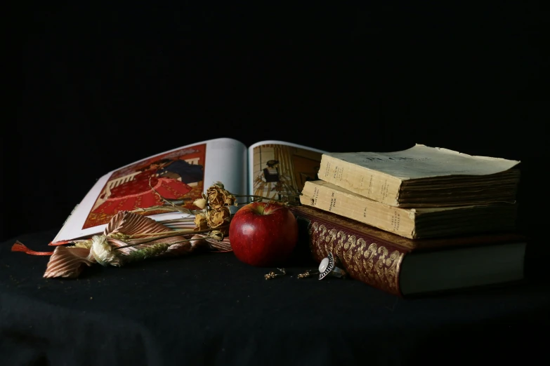 an apple laying on top of books next to a tattered tassel