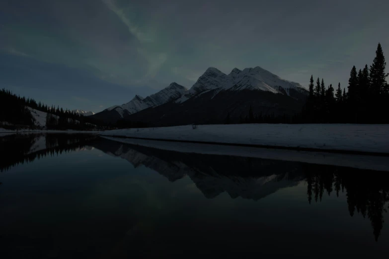 the night time sky is reflecting the mountains in a lake