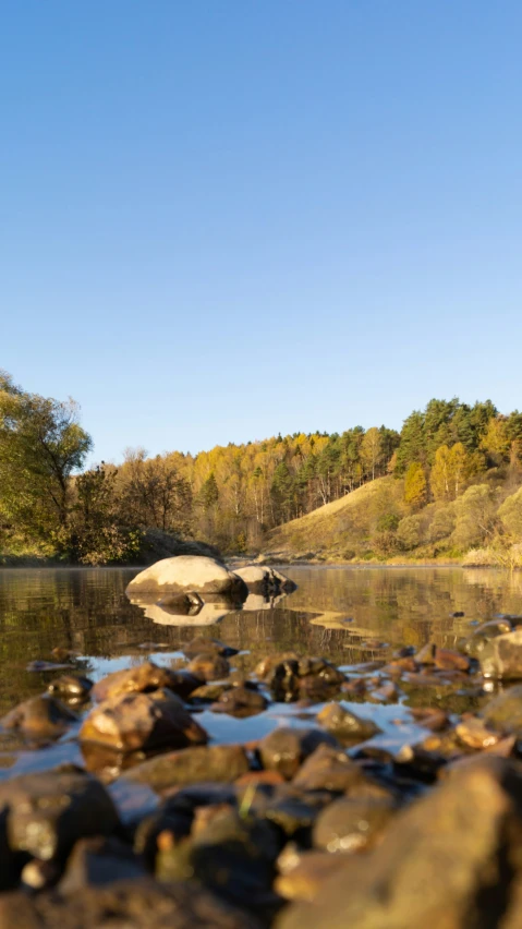 there are rocks sitting in the water and a bunch of rocks on the shore