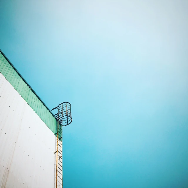 a green, rectangular fence against a blue sky