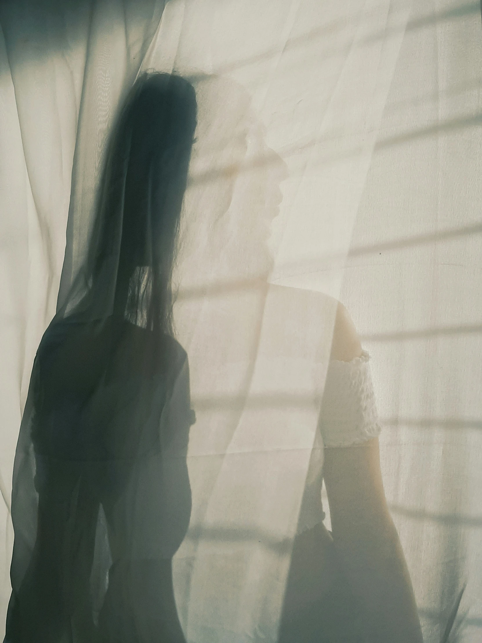 the woman is standing near the window in a dark room