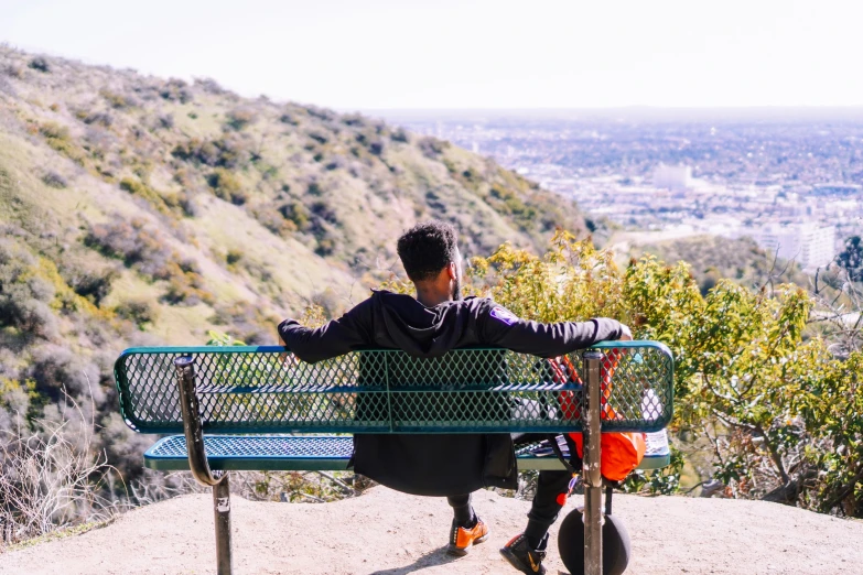 a person sitting on a bench looking at mountains
